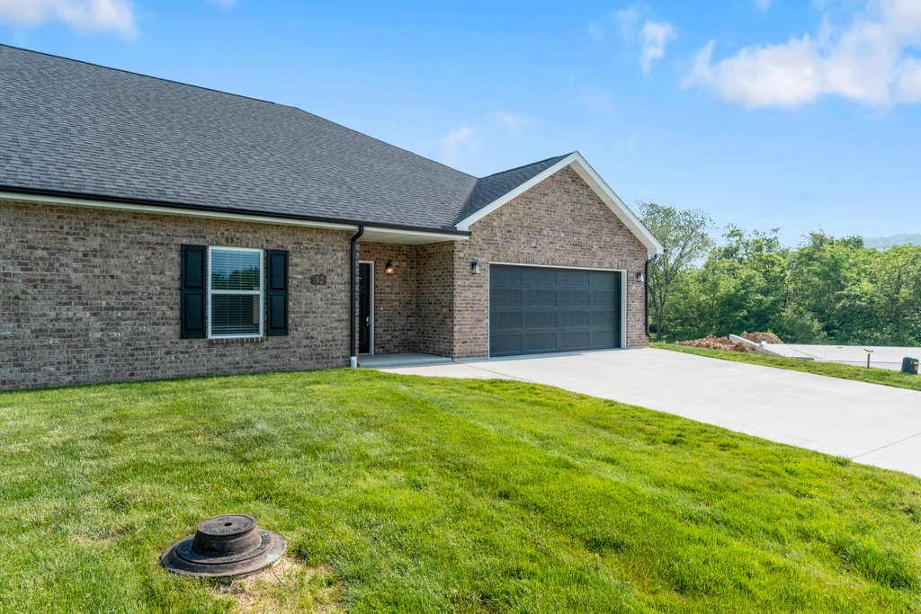 Modern brick house with attached garage and green lawn under a blue sky.