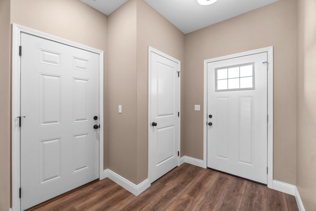 Interior hallway with three white doors and wood-look flooring.