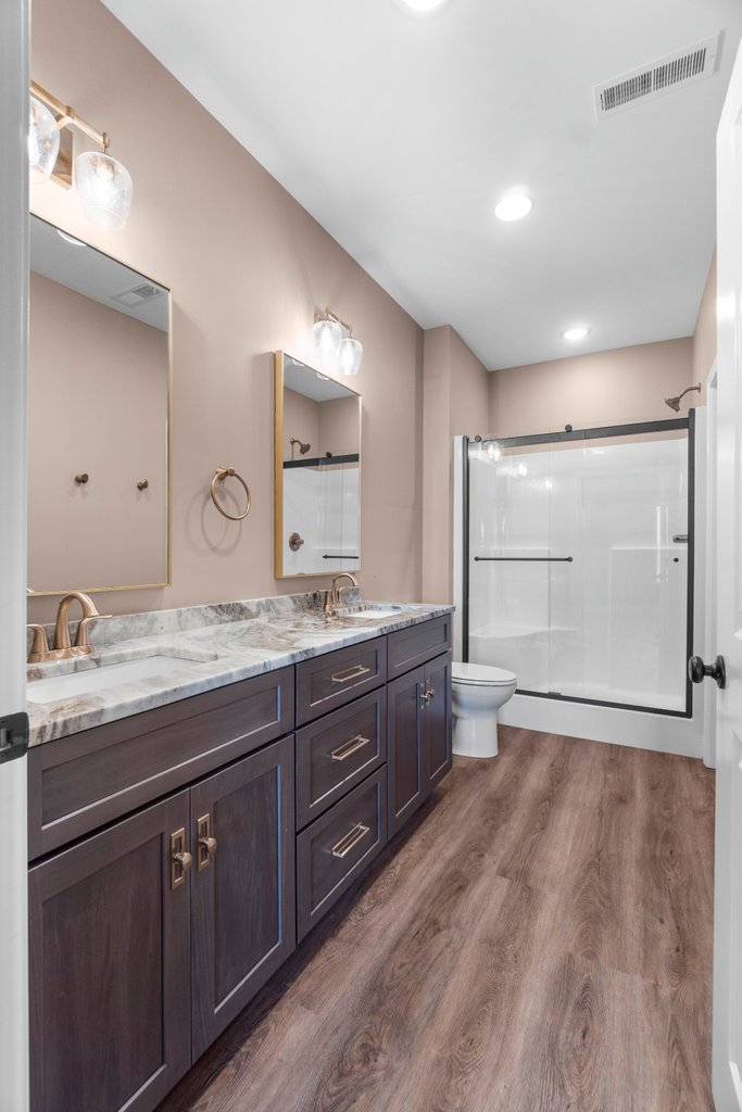 Modern bathroom with double vanity, marble countertop, and glass-enclosed shower.