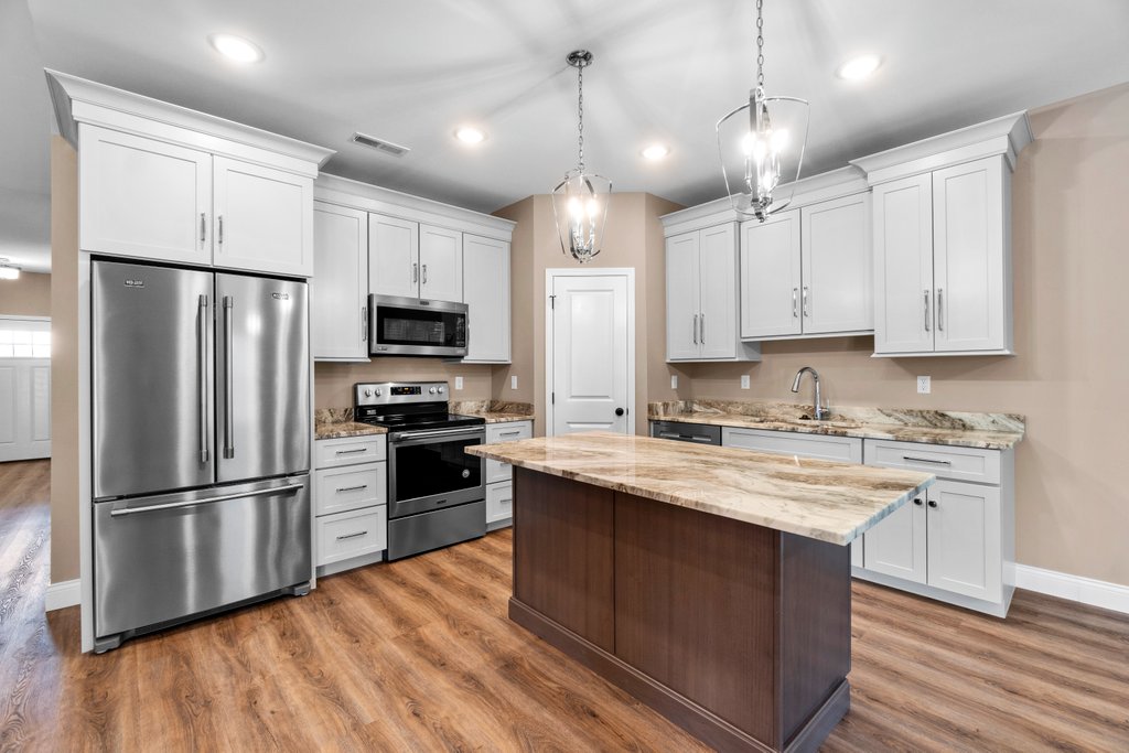 Modern kitchen with stainless steel appliances, white cabinets, granite countertops, and island.
